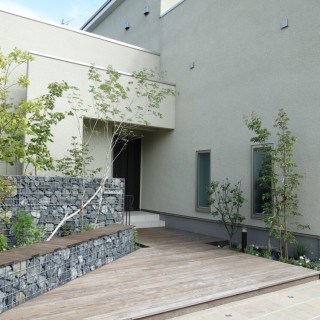 雑木が映えるロックウォールとウッドデッキの玄関周り