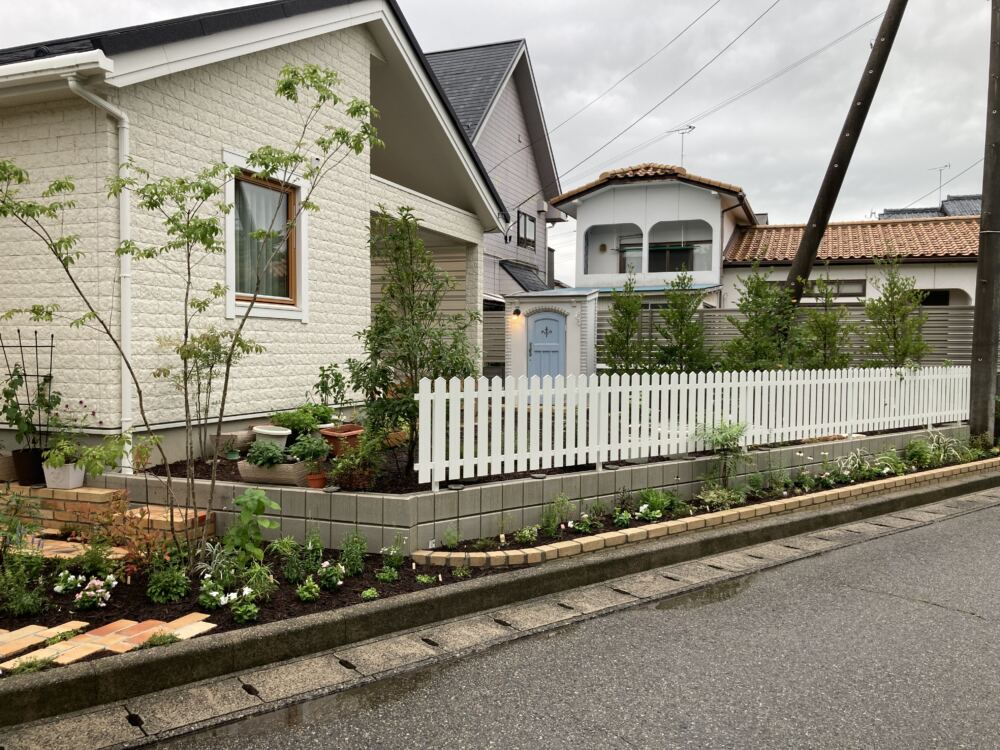 花壇前のアメリカンフェンス。
南欧風デザインの建物を引き立てます。
花壇は背丈のあるハーブを中心にコーディネート。今後フェンスにバラを誘引する予定で、バラが開花すると広がりのある絵画のような美しい景色が楽しめます。