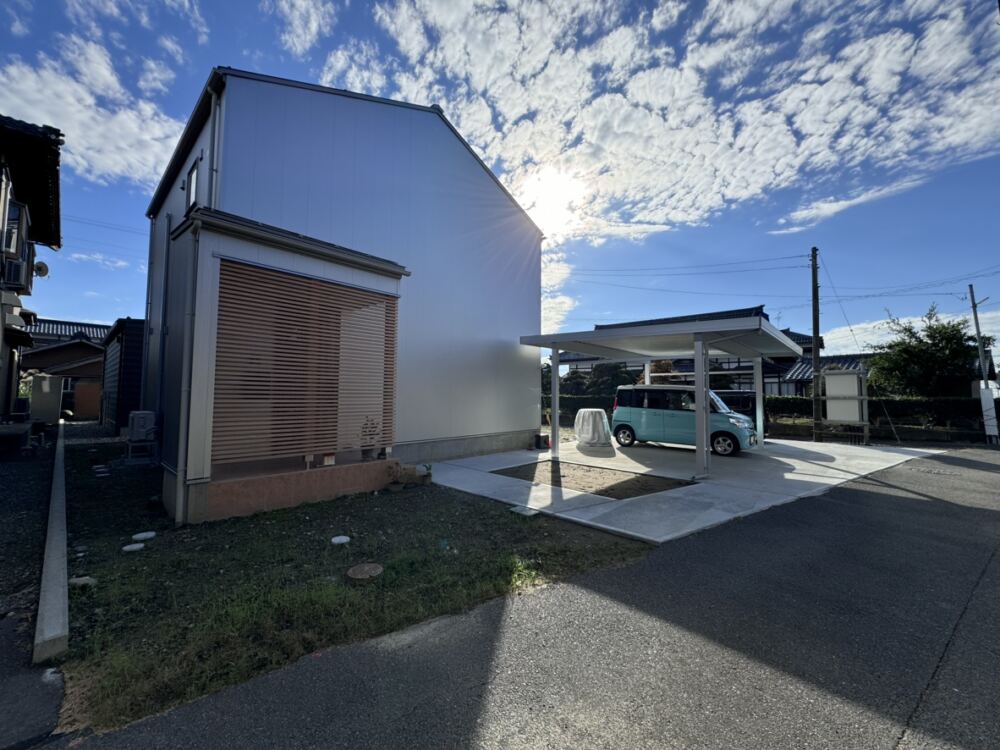 窓のないシルバーの外壁に横格子がアクセント入る外観。アプローチを挟んだ２つの植栽桝をデザインさせていただきました。