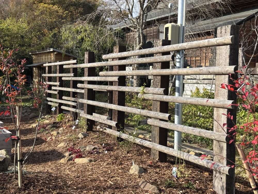 境界側には目隠しを兼ねた半割のフェンス。バラやクレマチスを絡ませたり、ハンギングが楽しめたりできます。
ウッドチップを敷くことで土壌の保湿・保温・泥はね防止だけでなく雑草の抑制にもなります。
また地被植物が時間の経過とともに繁茂するので、草取りの手間が軽減されます。