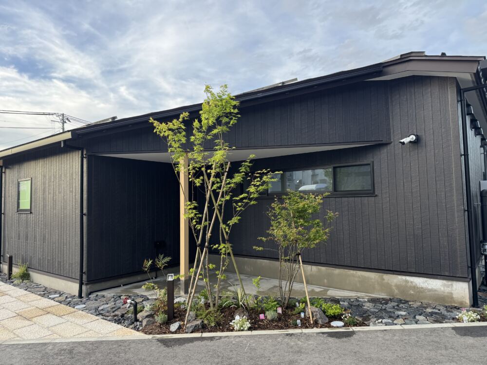シックな外壁を背景に、風にそよぐ高木と足元を彩る低木、グランドカバーをバランスよく配置しました。
敷地沿いには温かみのある風合いのサビ御影石の舗石を敷き詰め、美しい緑と自然石の質感が調和する、洗練された和モダンの景観をつくっています。